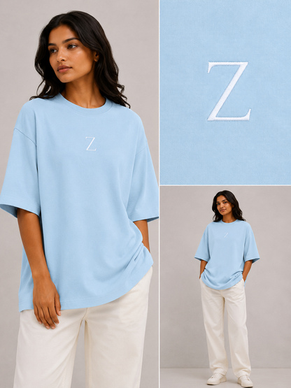 Zeroform , women oversized T-shirts  Woman wearing a light blue t-shirt with a 'Z' logo, standing against a neutral background.