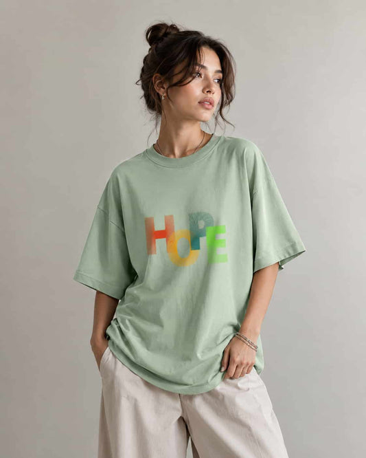Zeroform Person wearing a light green t-shirt with colorful letters on a plain background